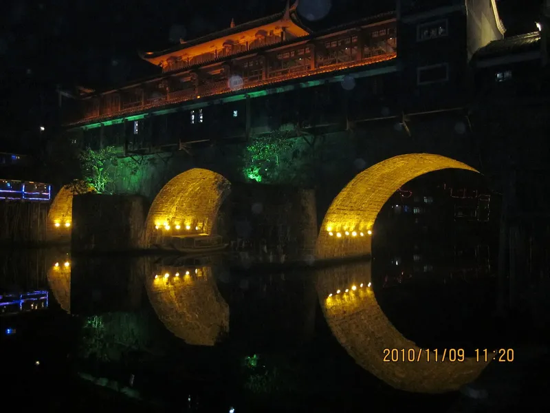 The Tuojiang River and Hong Bridge in Fenghuang Ancient Town at night, lanterns reflected in the water
