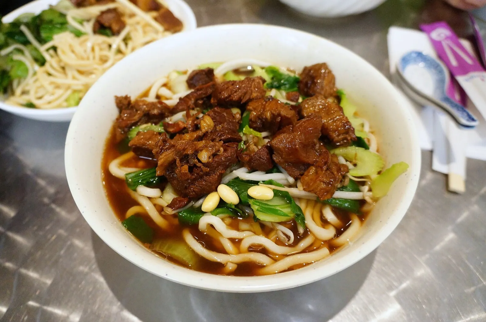 Steaming bowls of noodles and dumplings on a shared table at a Chinese restaurant