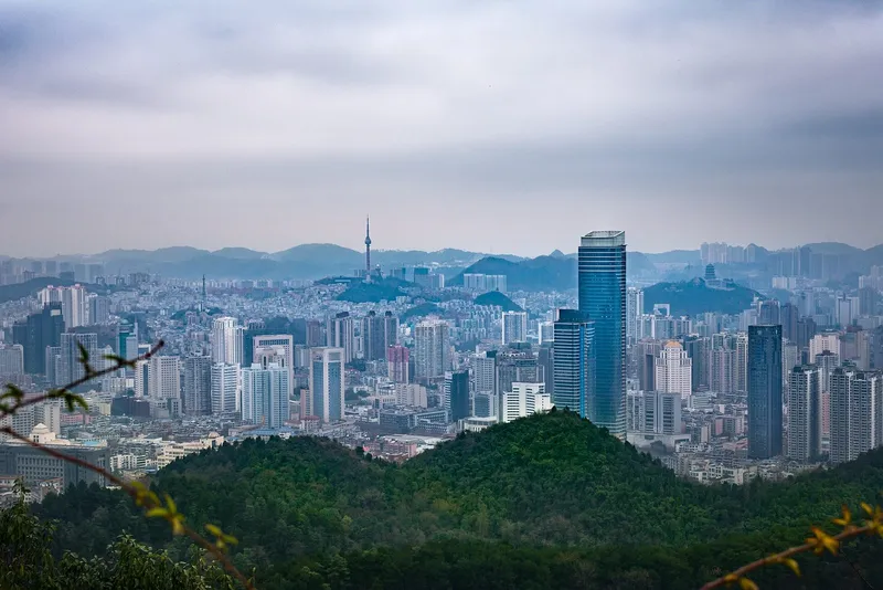 An elevated view over Guiyang's skyline of towers and hills under a summer sky
