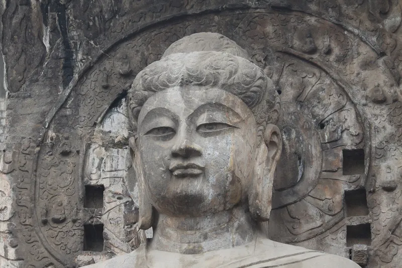 The giant Vairocana Buddha of the Fengxian Temple grotto at Longmen, carved into a limestone cliff above the Yi River in Luoyang