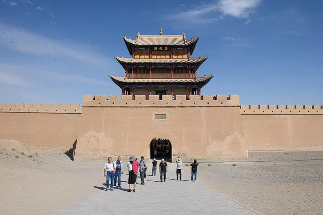 The gate tower of Jiayuguan Fort, the western end of the Ming Great Wall, rising above its ramparts against desert hills under a blue sky
