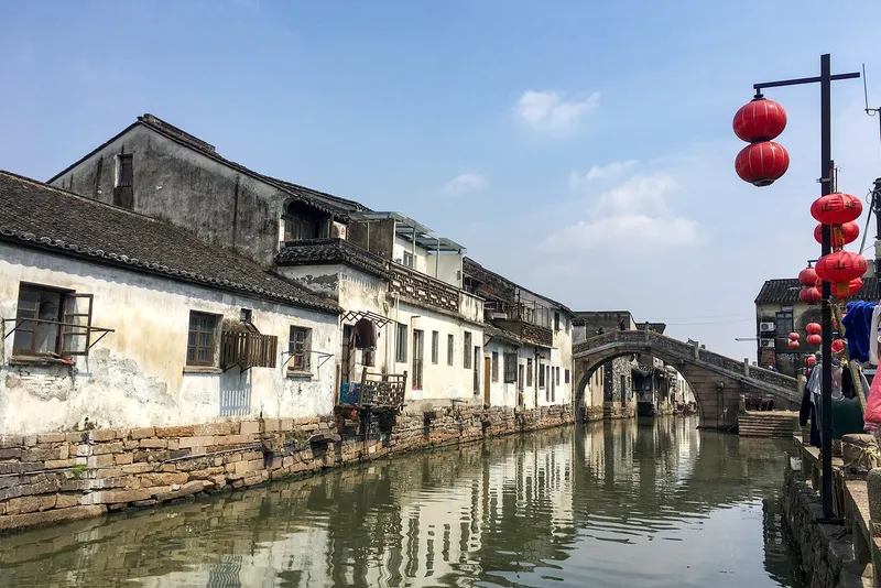 Whitewashed canal-side houses and a stone bridge on Pingjiang Road at dusk, Suzhou