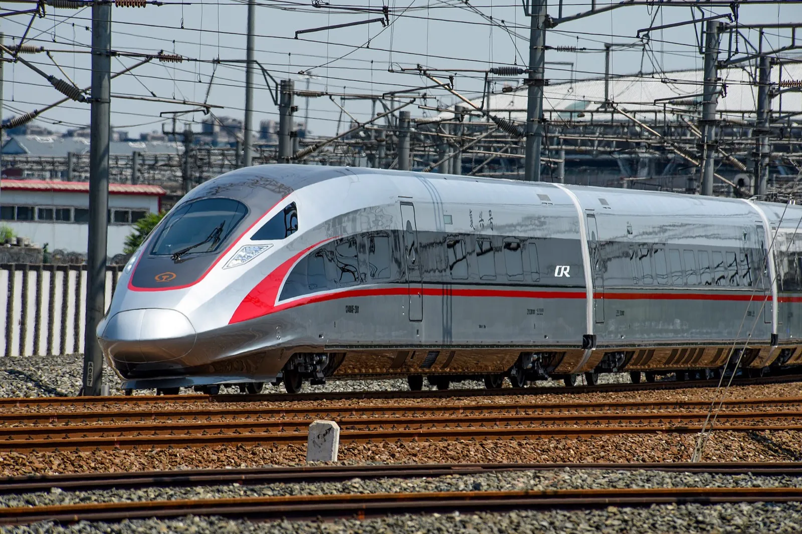 A sleek white high-speed train waiting at a modern glass-roofed platform in a Chinese railway station