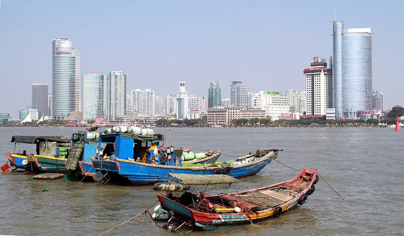 The Xiamen waterfront at dusk with Gulangyu Island's red-roofed villas across the harbor