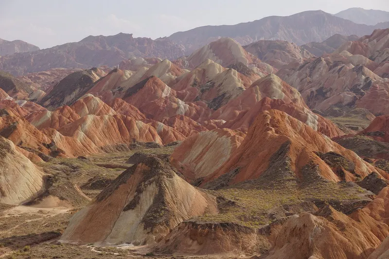 Banded red and gold hills of the Rainbow Danxia landform under evening light